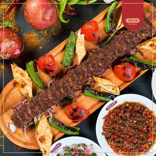 Adana kebabı, közlenmiş biber, domates ve lavaş ile servis